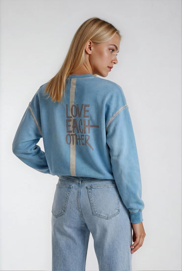 Back view of House of Malibu light blue sweatshirt with hand-painted design on the back which quotes "Love eachother"