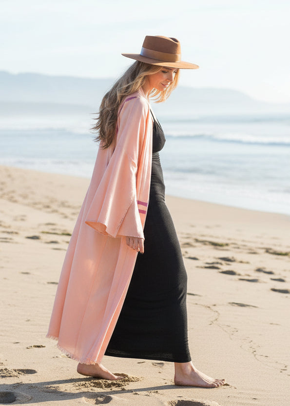 woman walking on the beach wearing a long peach linen kimono with hand-painted stripes by house of malibu