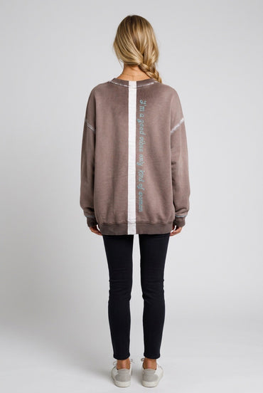 Person wearing a taupe hand-painted sweatshirt with text on the back