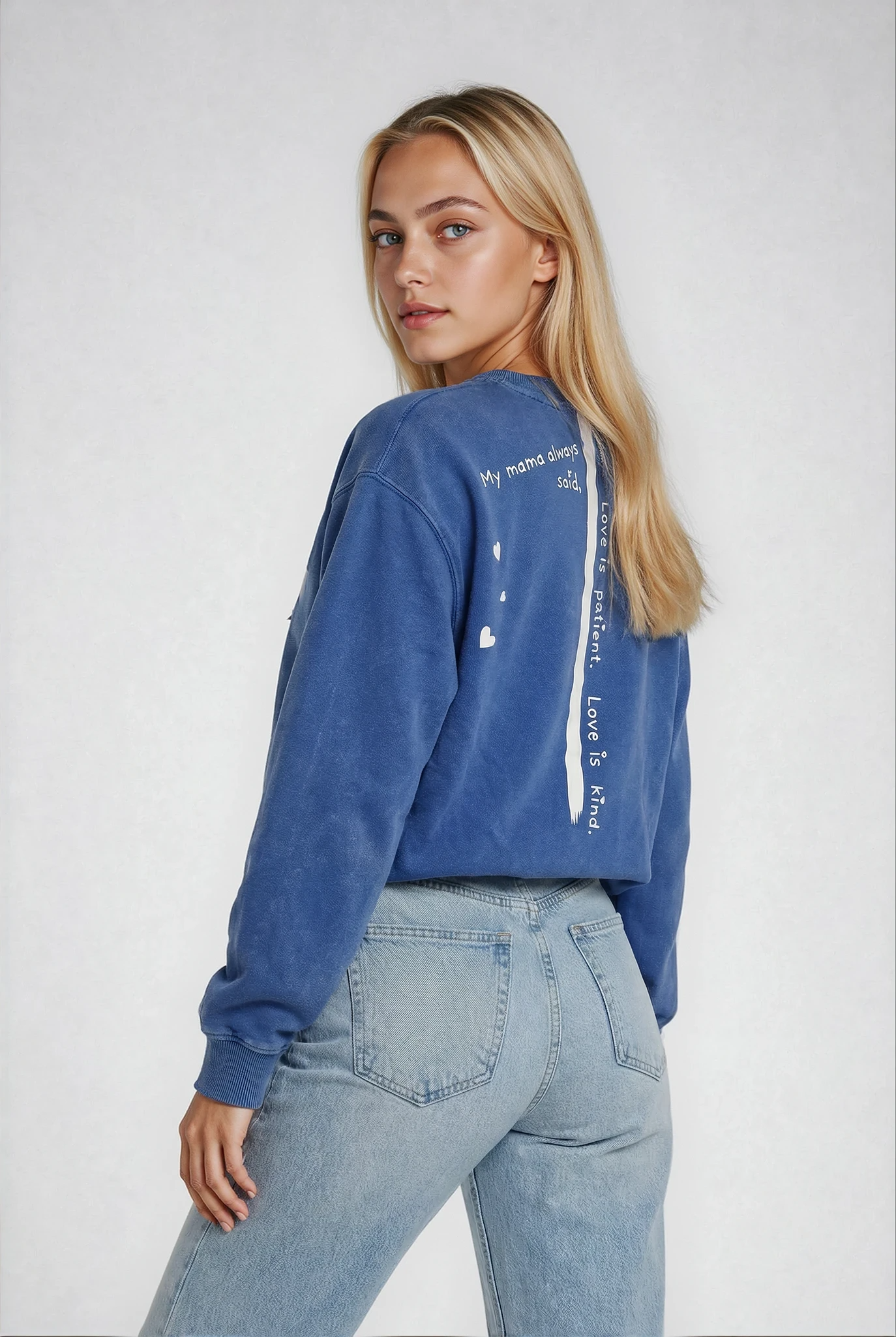 Blonde pretty girl wearing a blue House of Malibu sweatshirt with thier signature stripe and "mama always said Love is patient Love is kind" text on the back