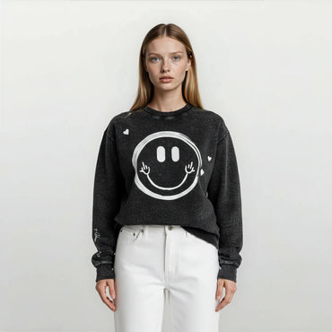 Close-up of a woman wearing an Onyx Wash oversized sweatshirt showing playful hand-drawn smiley face graphic and hearts scattered around.
