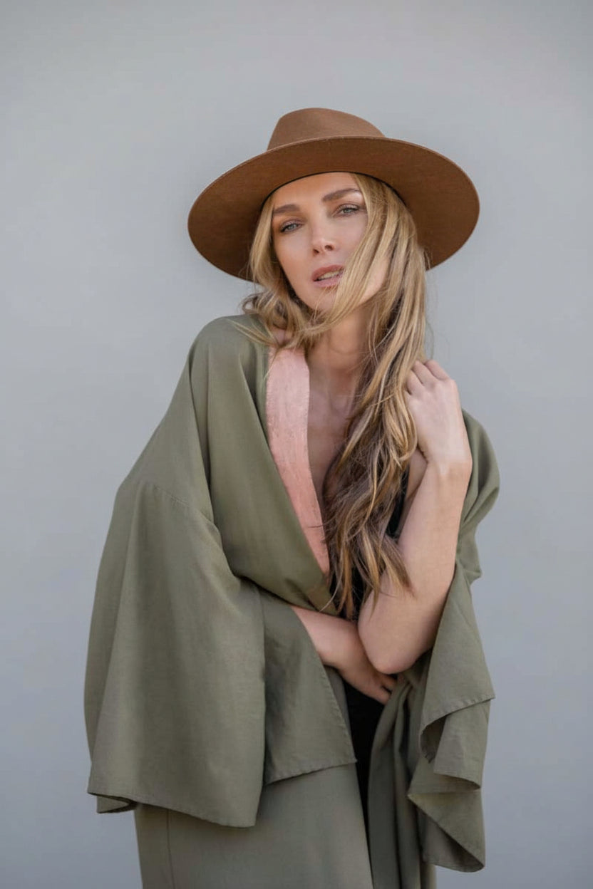 Woman wearing a long hand-painted house of malibu kimono in olive color  linen with painted blush color at front opening collar
