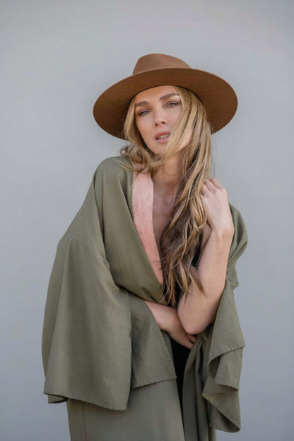Woman wearing a long hand-painted house of malibu kimono in olive color  linen with painted blush color at front opening collar
