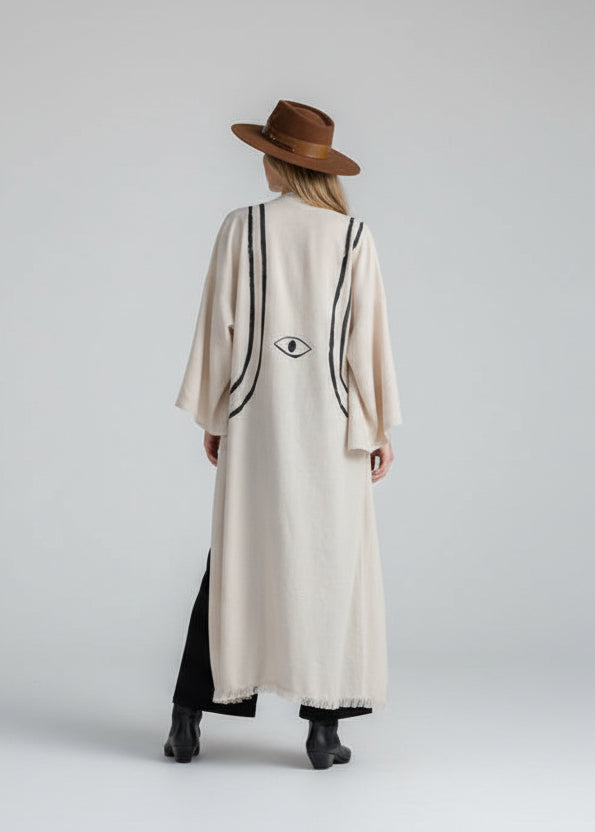 a long kimono jacket in color natural  oatmeal and painted with b lack lines resembling a harness and an eye motif