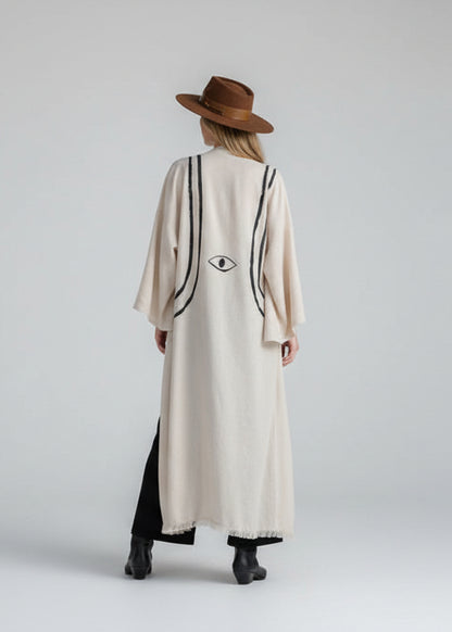a long kimono jacket in color natural  oatmeal and painted with b lack lines resembling a harness and an eye motif