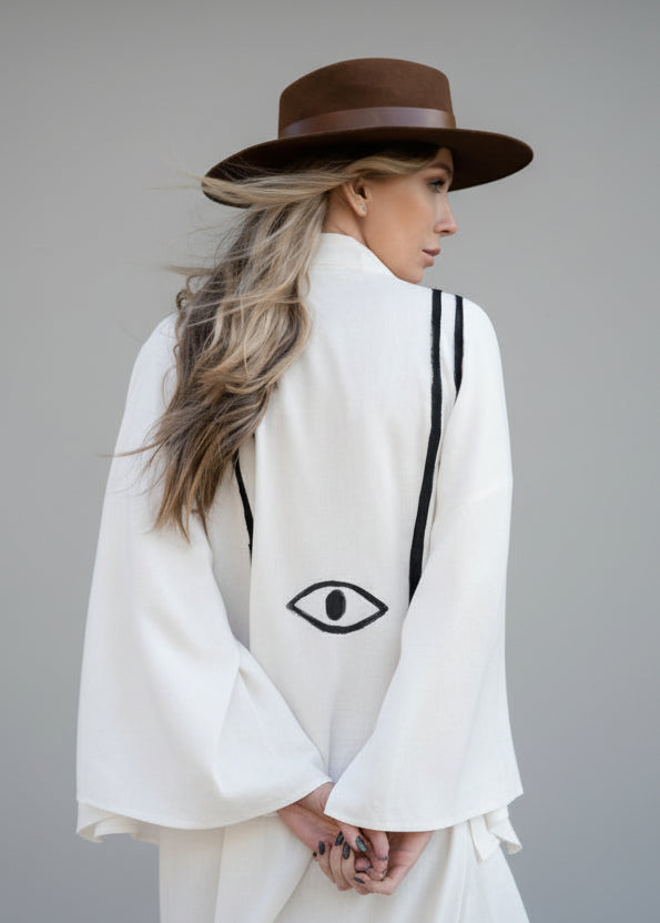 woman shown from the back  wearing a stunning hand-painted kimono jacket with double harness lines wraping around her back and an eye motif