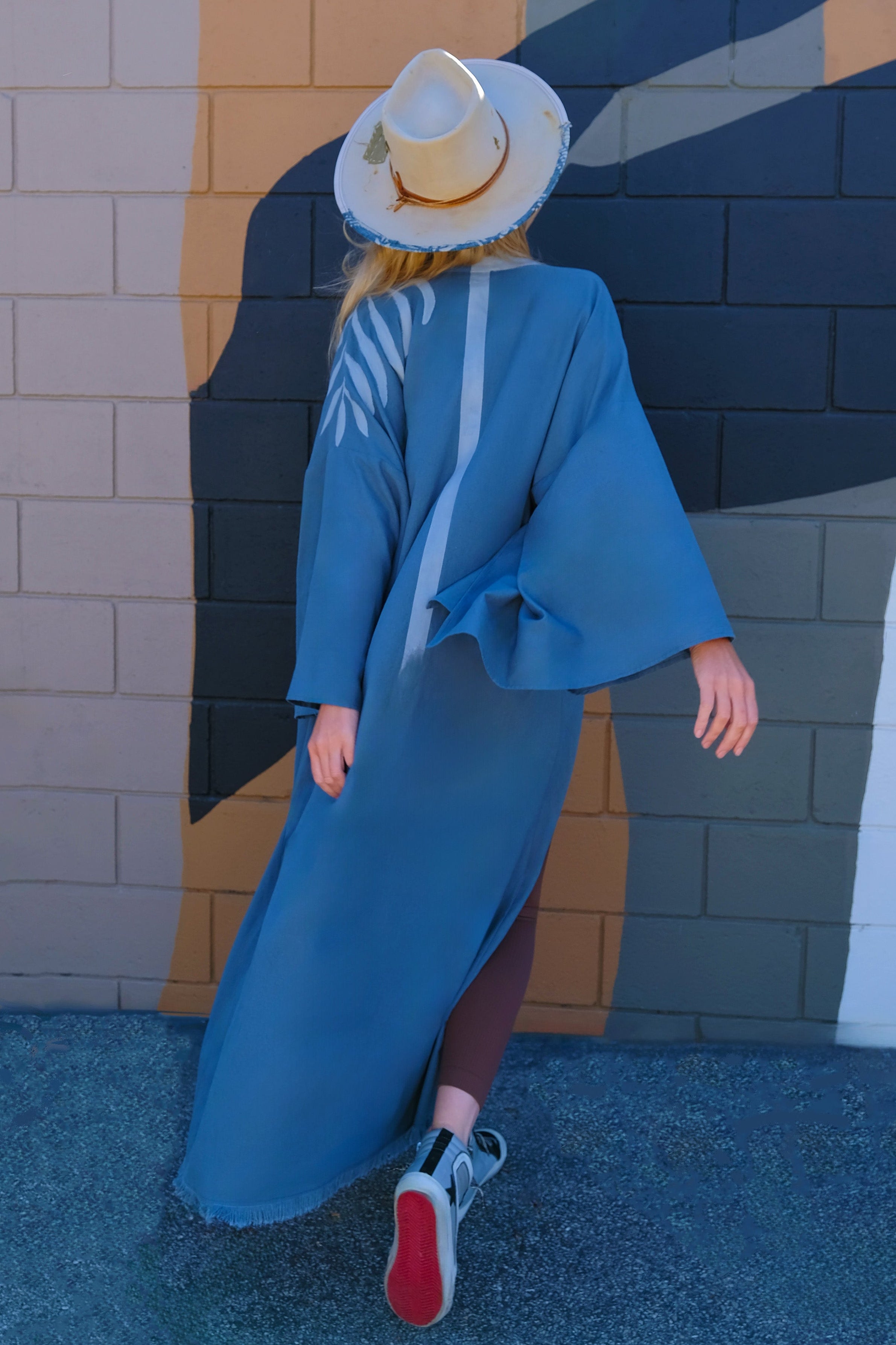 MALIBU CHIC WOMAN WEARING A BLUE GREEN KIMONO OUTFIT WITH A FEDORA HAT AND TENNIS SHOES