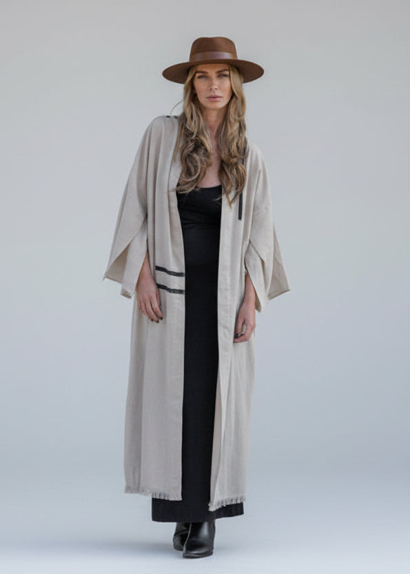 Woman wearing a long beige kimono with hand-painted black striped wrapping from back to front 