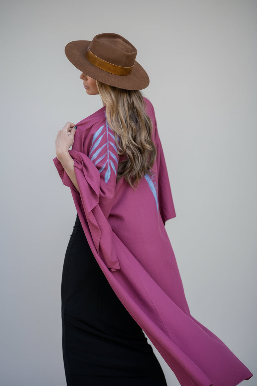 A woman wearing a hand-painted raspberry kimono with a periwinkle hand-painted design.