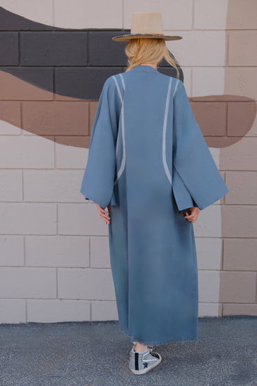 Woman wearing a blue long hand-painted kimono flowing dress wearing a  foglia hat and grey goose shoes