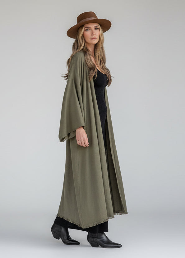 Woman wearing a long olive green kimono coat and brown hat 