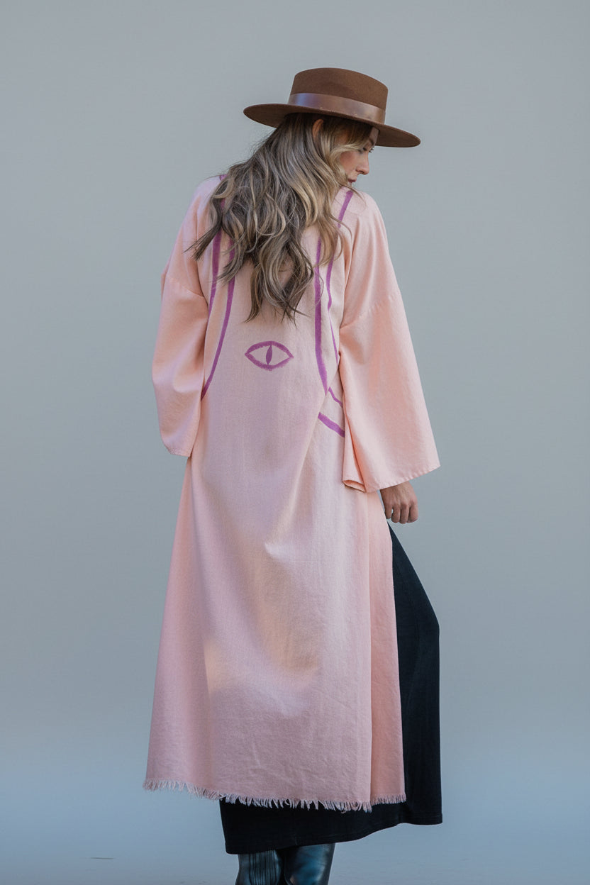 back view of a woman wearing a long peach linen kimono with hand-painted stripes  and evil eye by house of malibu 