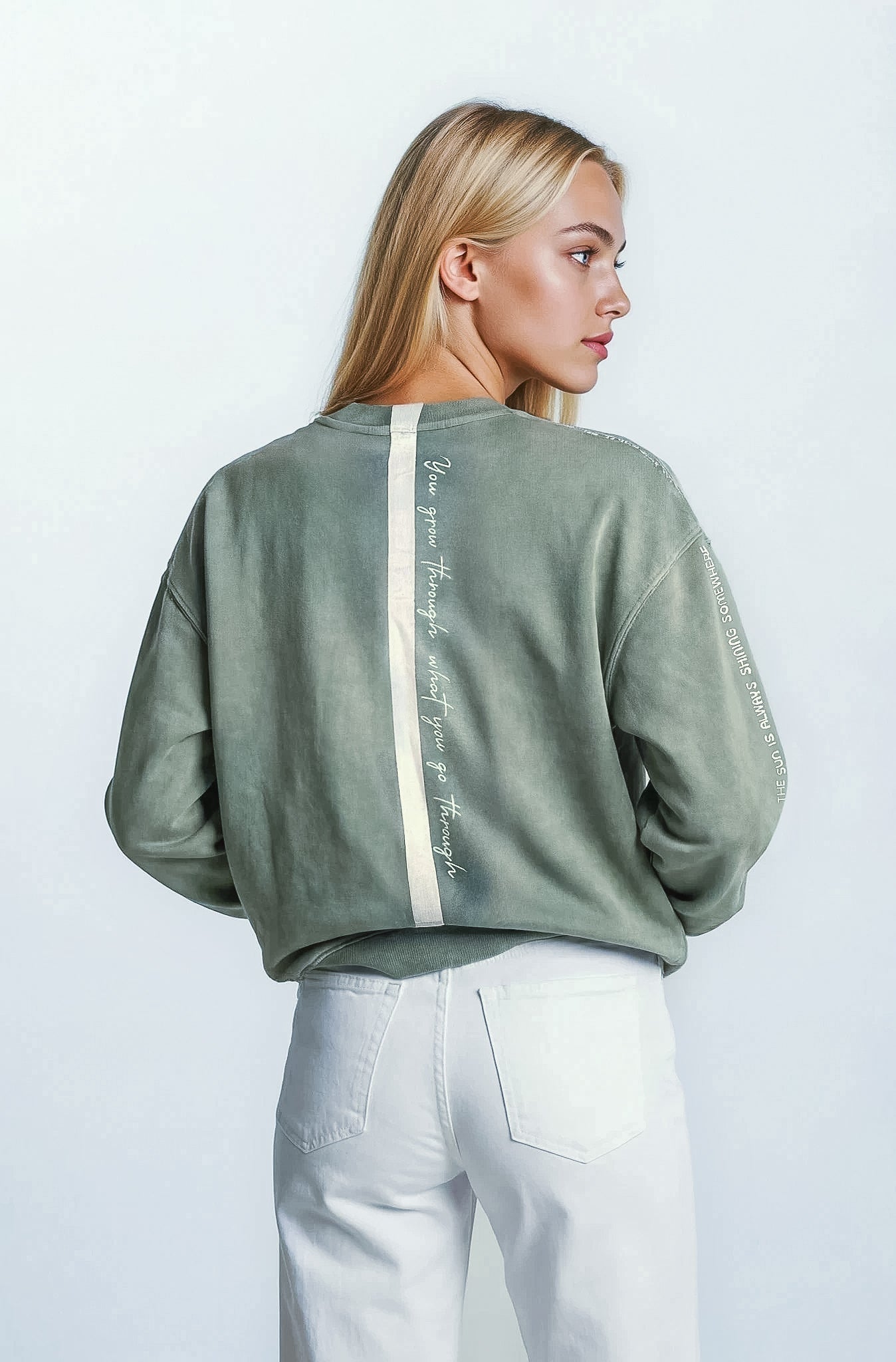 Woman wearing malibu sage sweatshirt with House of Malibu signature stripe on the back against against a white background