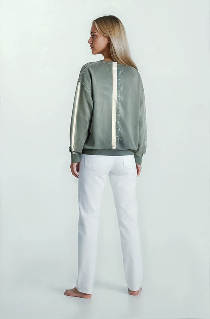 Woman standing backwards wearing a malibu sage garment dyed sweatshirt hand-painted by House of Malibu with a stripe  quote painted down the back 