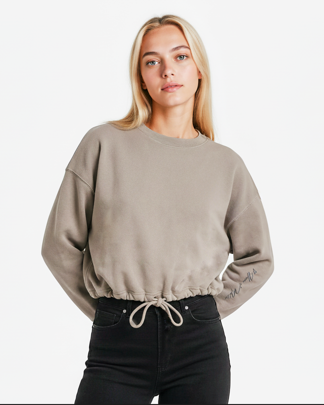 Woman wearing a beige cropped  cotton sweatshirt and black pants 