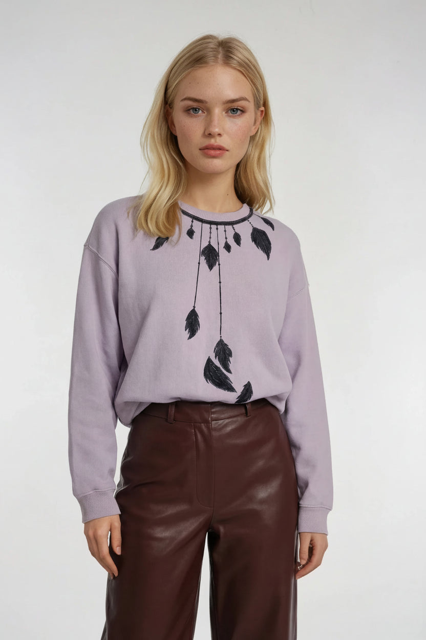 Woman wearing a HOUSE OF MALIBU light purple sweater with feather dream catcher hand-painted design