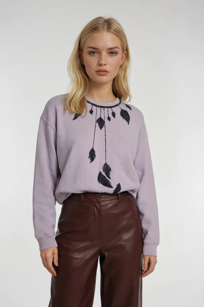 Woman wearing a HOUSE OF MALIBU light purple sweater with feather dream catcher hand-painted design