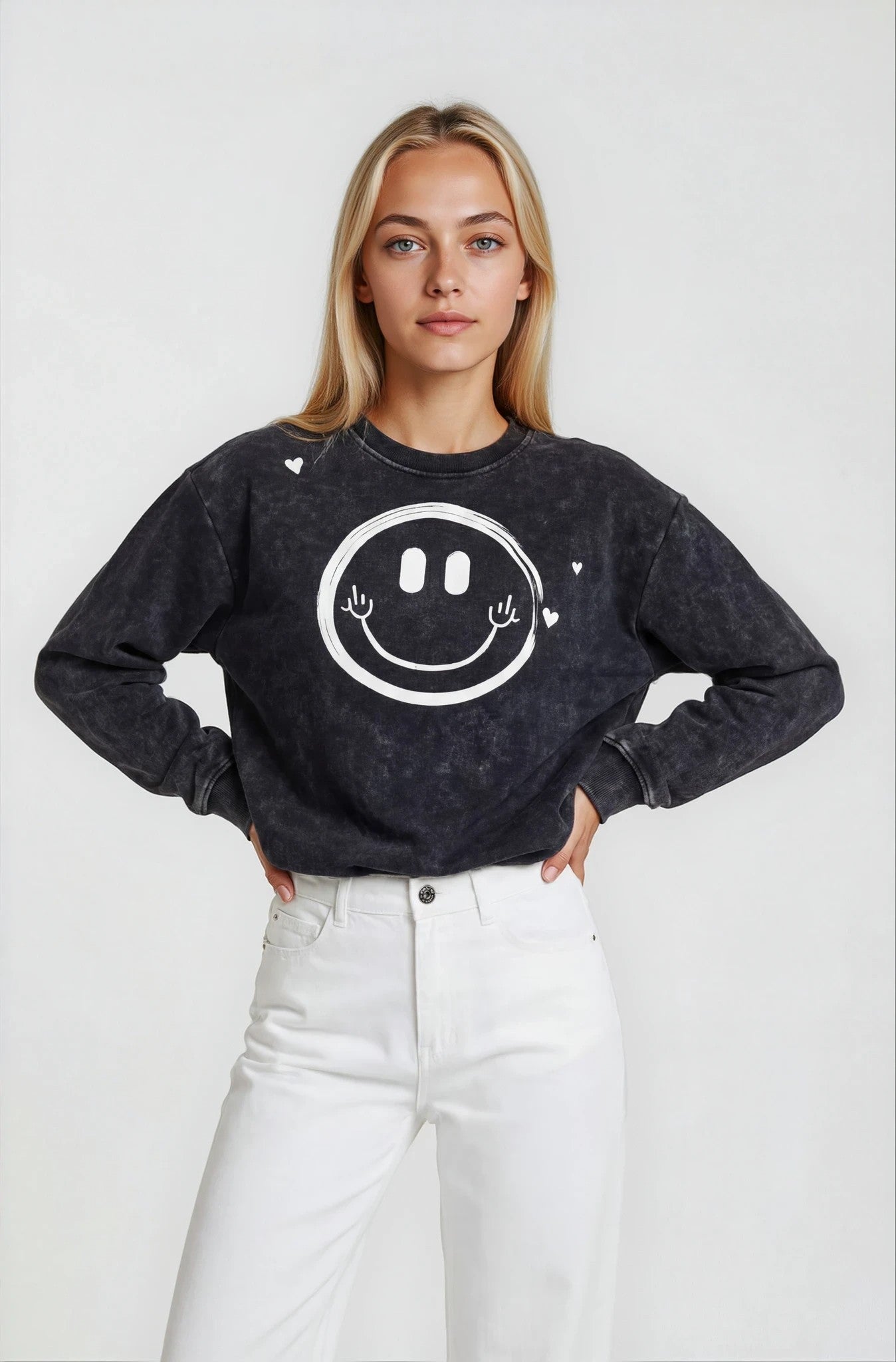 Person wearing a black sweatshirt with a smiley face design on a white background