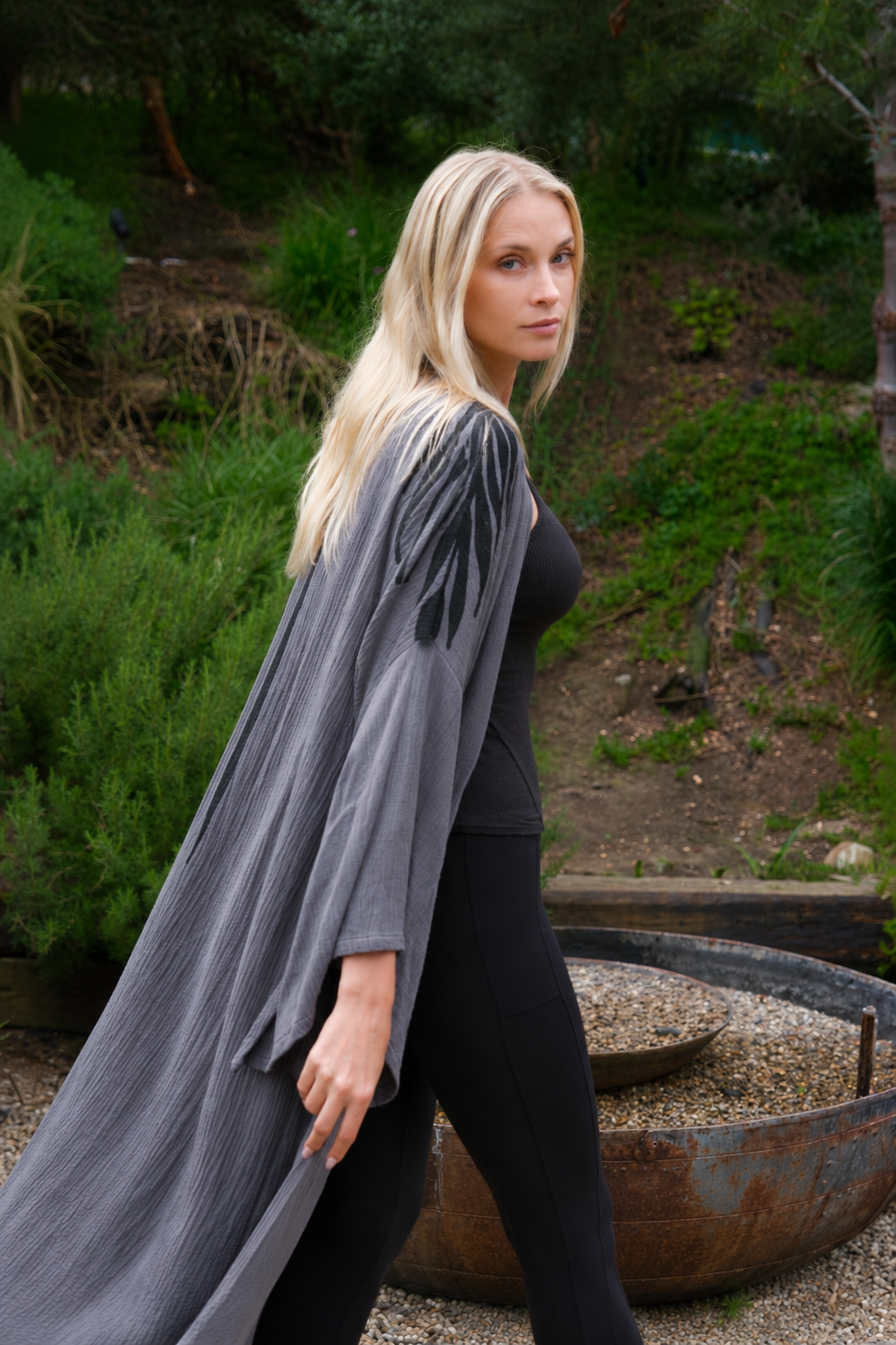 Woman wearing a gray Kimono robe in an garden outdoor setting with greenery.