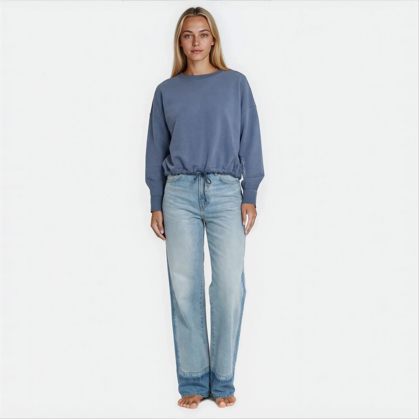 A woman wearing a blue cropped premium cotton french terry sweatshirt with adjustable waist band.