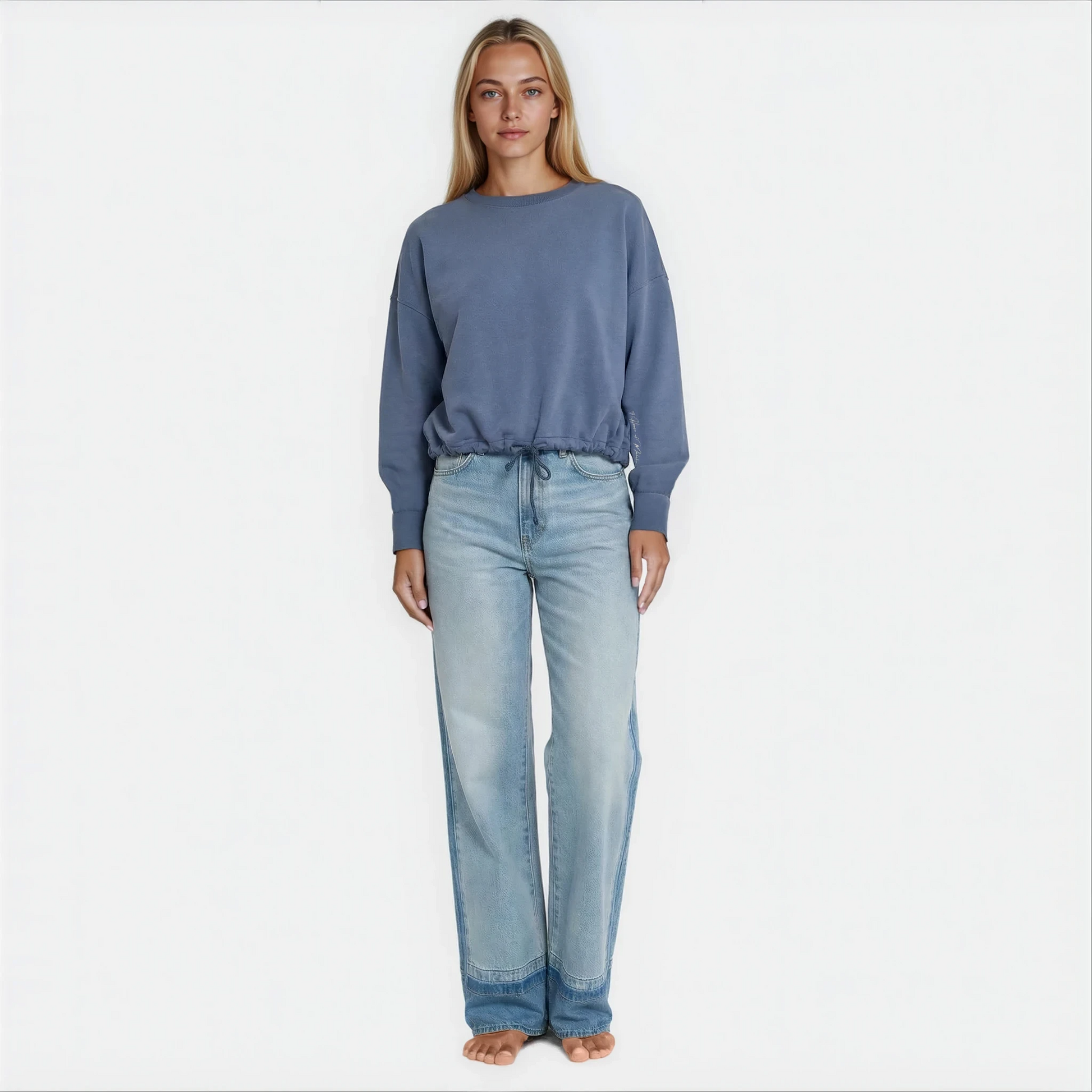 A woman wearing a blue cropped premium cotton french terry sweatshirt with adjustable waist band.