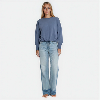 A woman wearing a blue cropped premium cotton french terry sweatshirt with adjustable waist band.