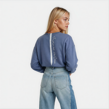 Back view of a woman wearing a super cute printed blue sweatshirt by House of Malibu.