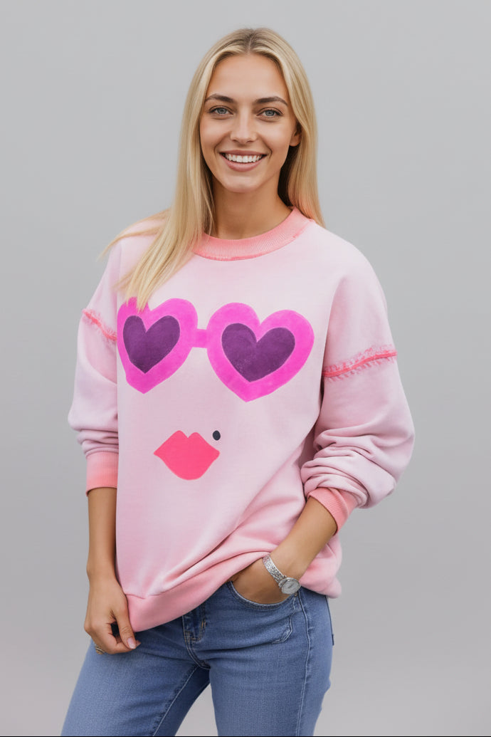 Woman wearing a House of Malibu Washed Coral Sweatshirt with Hearts and lips on the front