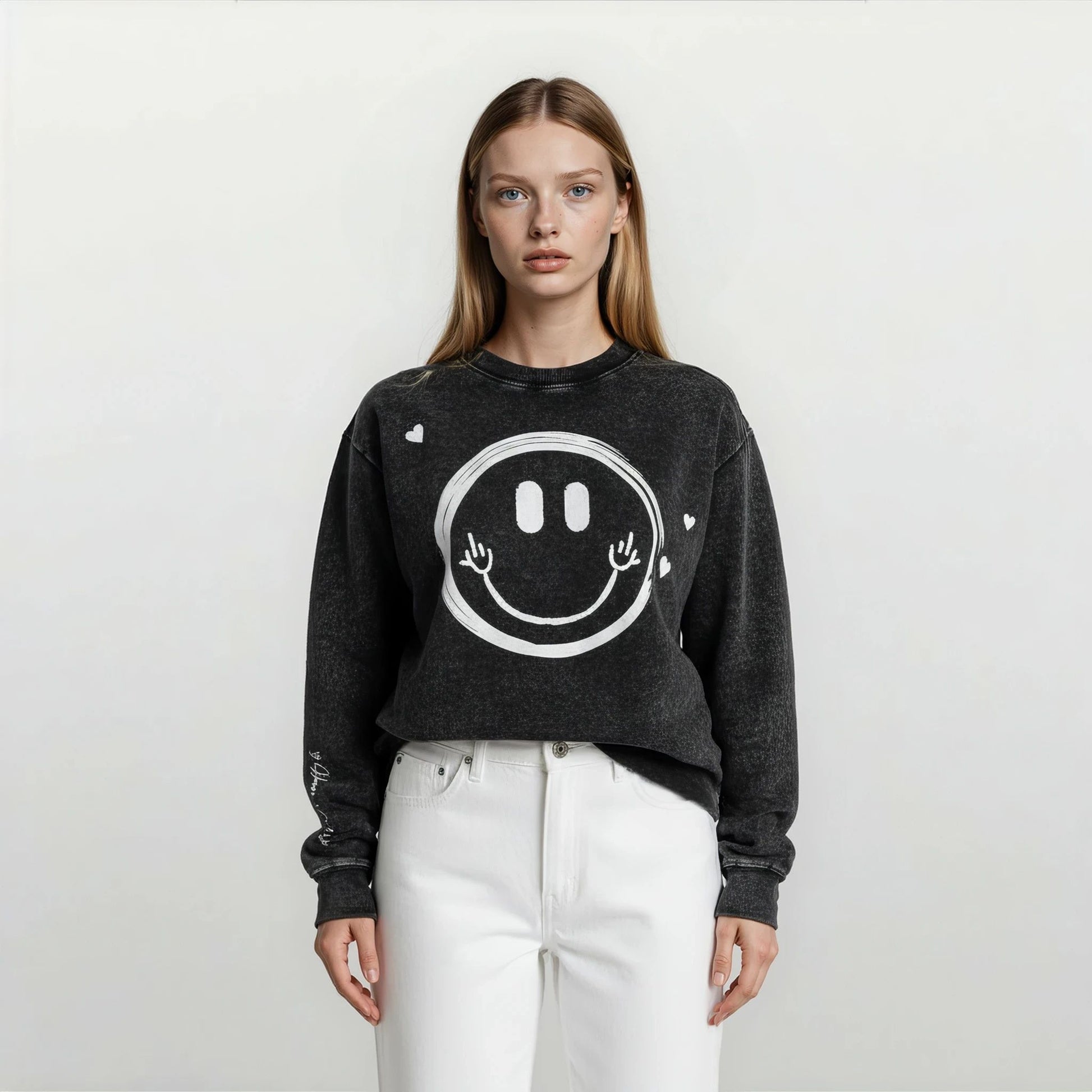 Close-up of a woman wearing an Onyx Wash oversized sweatshirt showing playful hand-drawn smiley face graphic and hearts scattered around.