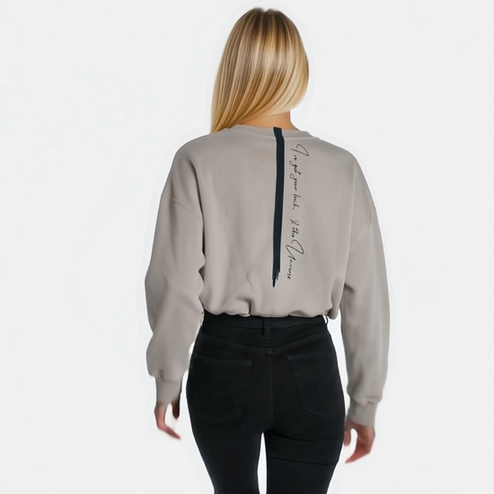 video of a woman walking away showing off her cropped sandstone affirmation cotton sweatshirt with a quote down the back