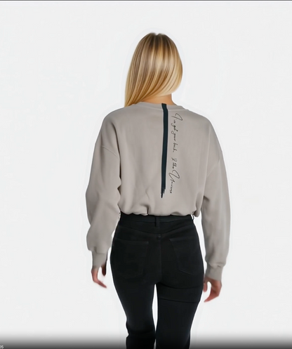 video of a woman walking away showing off her cropped sandstone affirmation cotton sweatshirt with a quote down the back